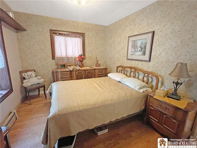 bedroom with wallpapered walls, baseboard heating, and light wood-type flooring