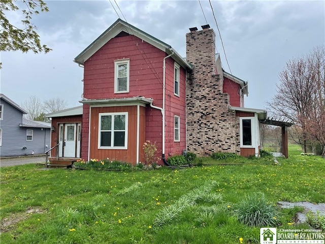rear view of house with a yard and a chimney