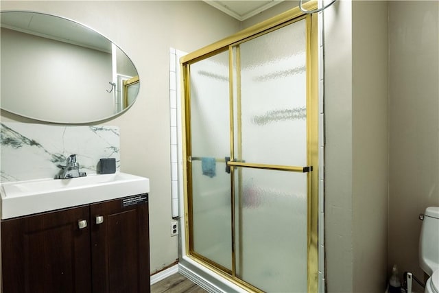 bathroom with vanity, crown molding, hardwood / wood-style floors, toilet, and a shower with shower door