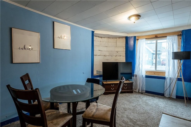 carpeted dining space with crown molding