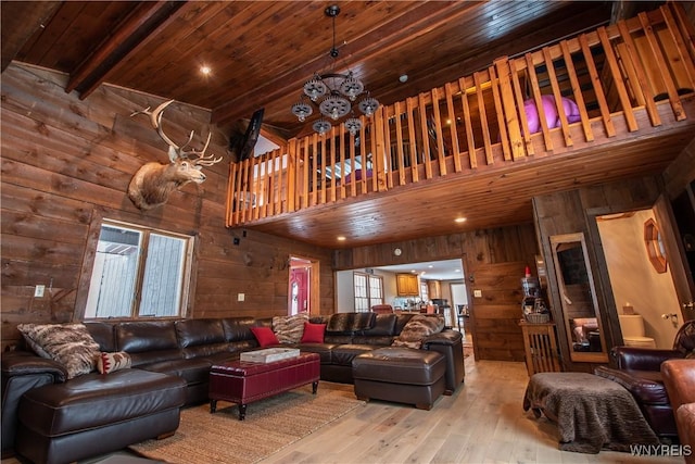 living area featuring beamed ceiling, wooden walls, wood ceiling, and light wood-style flooring