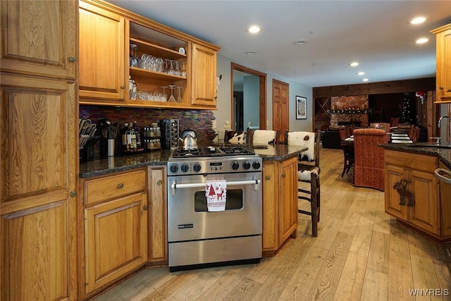 kitchen with light wood finished floors, a sink, open floor plan, gas range, and brown cabinets