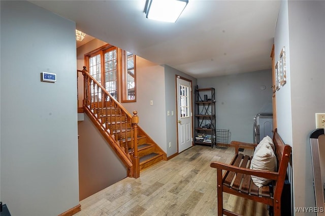 living area with washer and dryer, stairway, baseboards, and wood finished floors