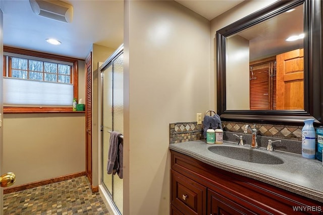 bathroom with decorative backsplash, a shower stall, vanity, and baseboards