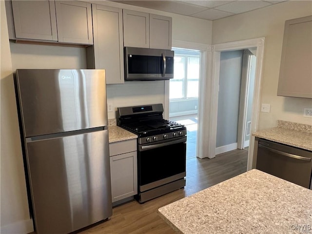 kitchen featuring hardwood / wood-style floors, a paneled ceiling, stainless steel appliances, and gray cabinets