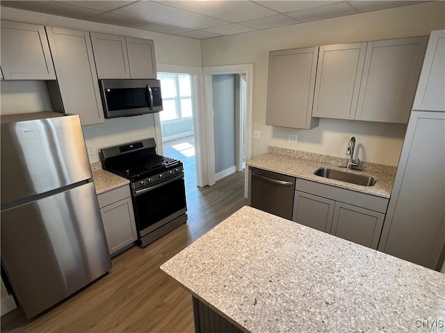 kitchen featuring a paneled ceiling, sink, dark hardwood / wood-style floors, gray cabinets, and appliances with stainless steel finishes