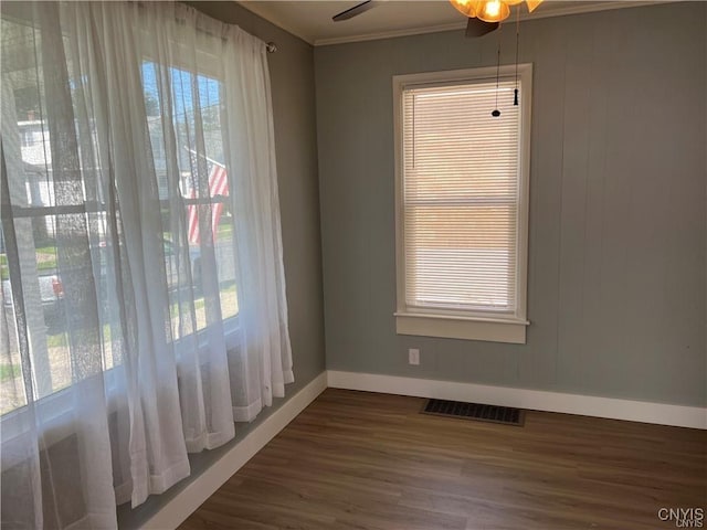 unfurnished dining area with ornamental molding, ceiling fan, and dark wood-type flooring