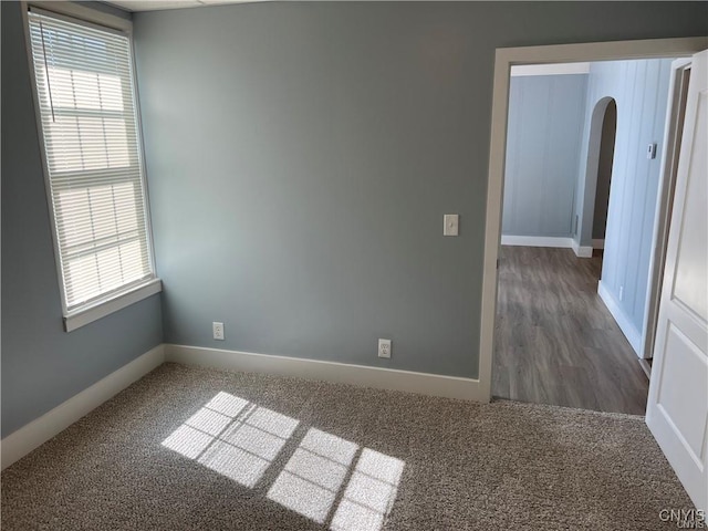 spare room featuring a healthy amount of sunlight and dark hardwood / wood-style flooring