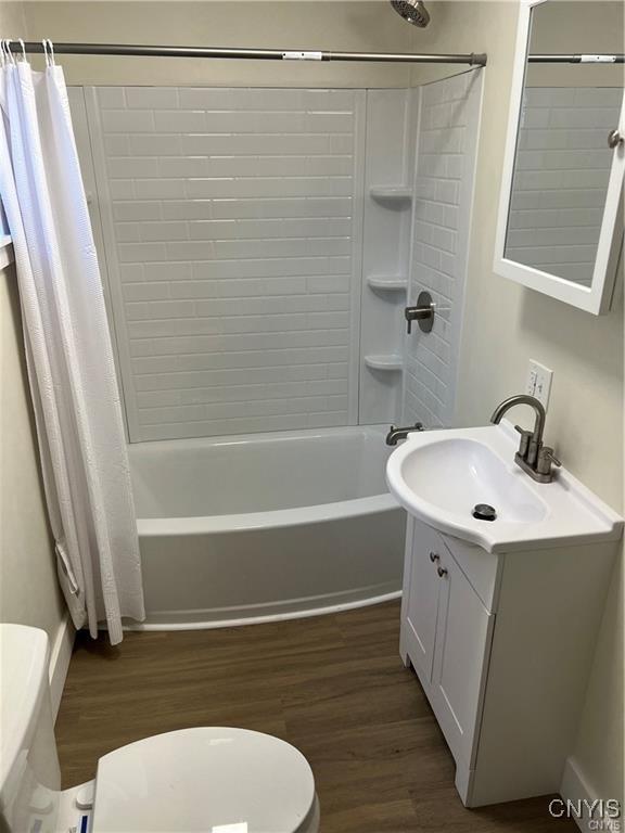 full bathroom with hardwood / wood-style flooring, vanity, toilet, and shower / tub combo