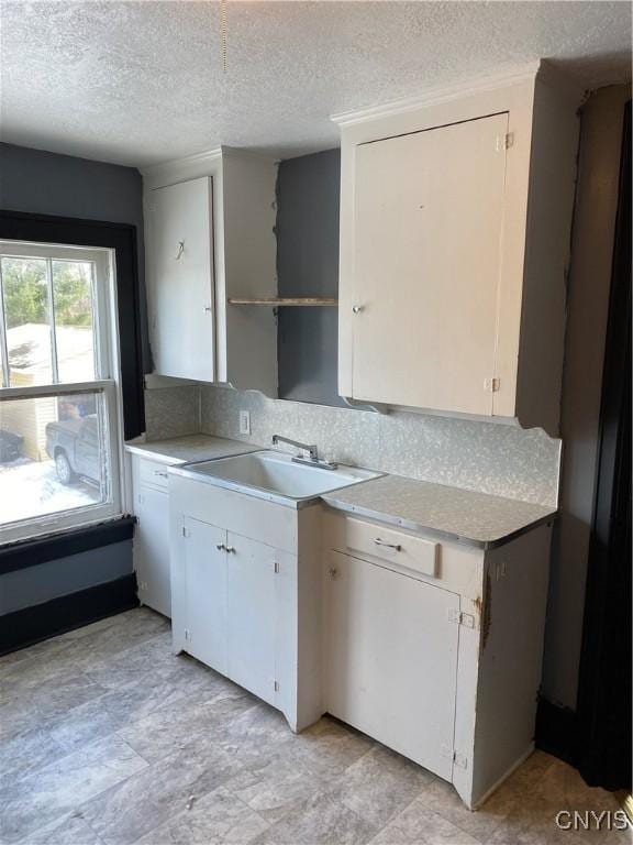 kitchen featuring white cabinets, sink, and a textured ceiling