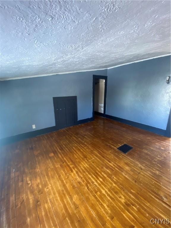 spare room featuring a textured ceiling and dark hardwood / wood-style floors