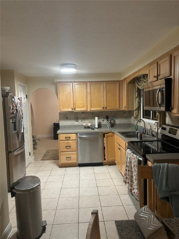 kitchen with light brown cabinets, sink, decorative backsplash, light tile patterned floors, and appliances with stainless steel finishes