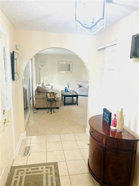 hallway featuring a textured ceiling and light colored carpet