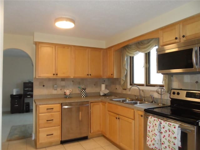 kitchen featuring sink, tasteful backsplash, light tile patterned floors, light brown cabinetry, and appliances with stainless steel finishes