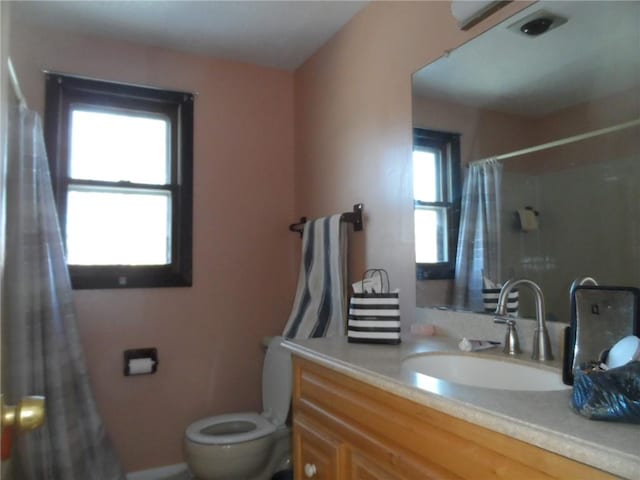 bathroom with a shower with shower curtain, vanity, toilet, and a healthy amount of sunlight