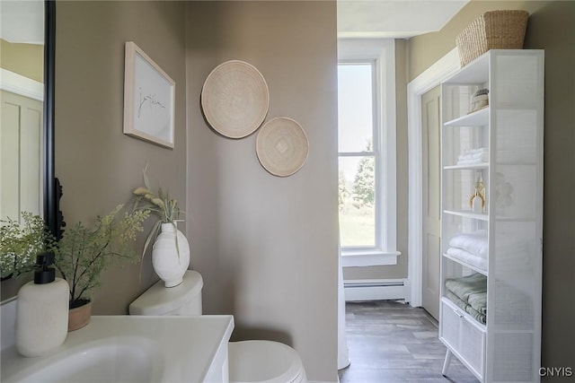 bathroom with hardwood / wood-style flooring, toilet, and a baseboard heating unit