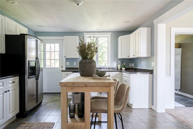 kitchen featuring tile patterned flooring, stainless steel fridge with ice dispenser, white cabinetry, and sink