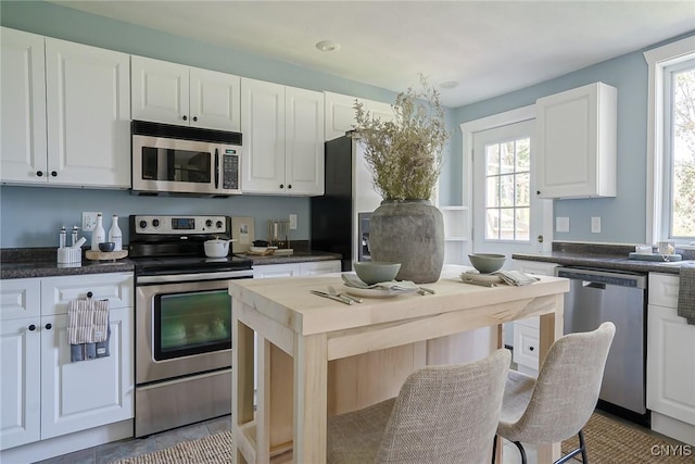 kitchen featuring white cabinets, a healthy amount of sunlight, light tile patterned flooring, and stainless steel appliances