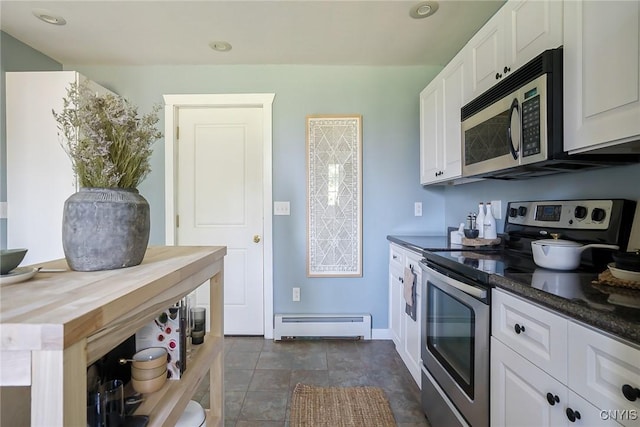 kitchen featuring wood counters, white cabinets, a baseboard heating unit, and appliances with stainless steel finishes