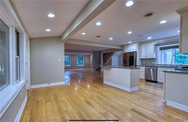 kitchen featuring light hardwood / wood-style flooring, white cabinetry, backsplash, stainless steel appliances, and a center island