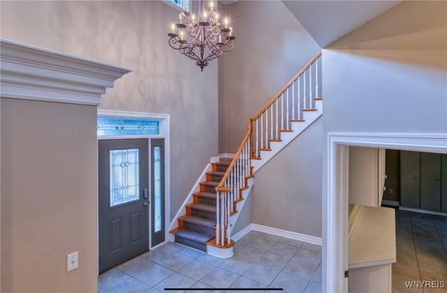 tiled entryway featuring a towering ceiling and a chandelier