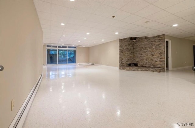 unfurnished living room featuring a baseboard heating unit and a paneled ceiling