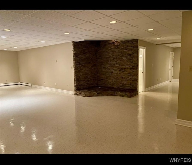 basement featuring a paneled ceiling and a baseboard radiator