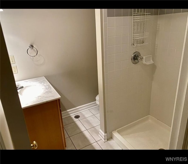 bathroom with vanity, toilet, tile patterned flooring, and a tile shower