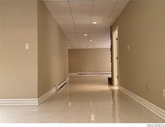 corridor with a drop ceiling and a baseboard radiator