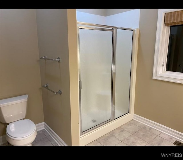 bathroom with a shower with door, tile patterned flooring, and toilet