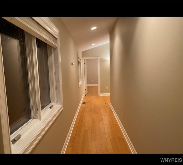 hallway featuring lofted ceiling and light hardwood / wood-style flooring