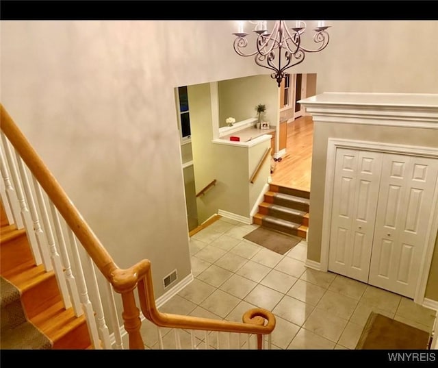 staircase featuring an inviting chandelier and tile patterned flooring