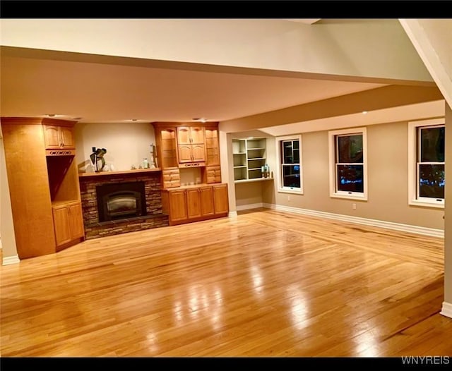 unfurnished living room featuring light wood-type flooring, built in features, and a fireplace