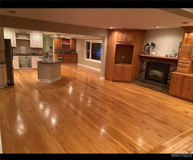 unfurnished living room featuring a stone fireplace and light hardwood / wood-style flooring