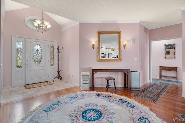 entrance foyer featuring ornamental molding, wood-type flooring, lofted ceiling, and a notable chandelier