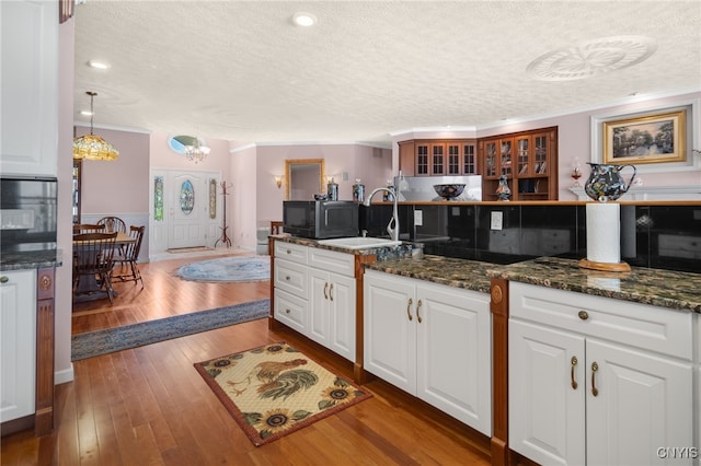 kitchen featuring white cabinetry, a textured ceiling, hanging light fixtures, and dark wood-type flooring