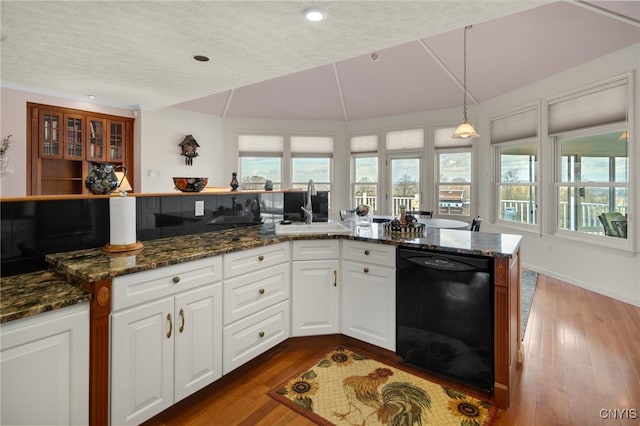 kitchen with dark wood-type flooring, sink, dark stone countertops, black dishwasher, and white cabinetry