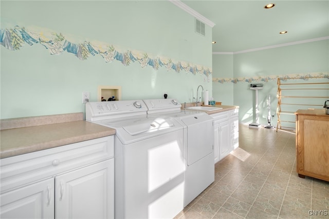 clothes washing area with crown molding, cabinets, sink, and washing machine and clothes dryer