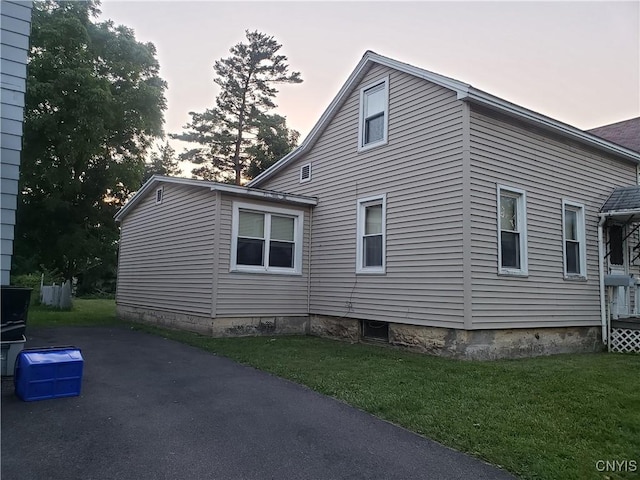 property exterior at dusk featuring a lawn