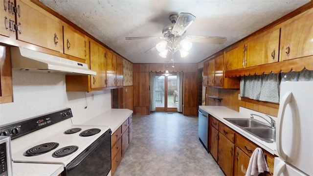 kitchen featuring ceiling fan, wood walls, white appliances, and sink