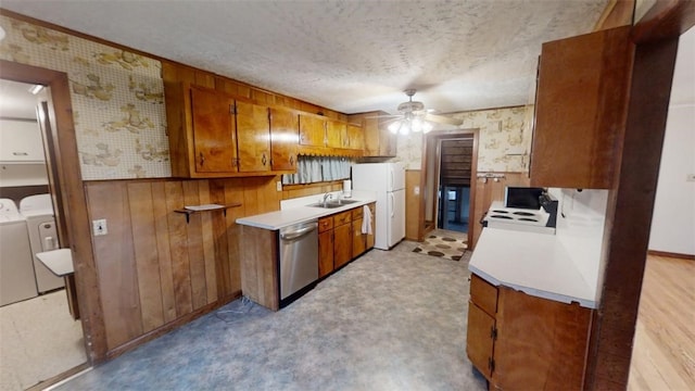 kitchen featuring washing machine and clothes dryer, wooden walls, stainless steel dishwasher, and white refrigerator