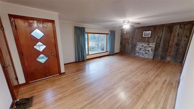 entryway featuring wood walls, ceiling fan, light hardwood / wood-style floors, and crown molding