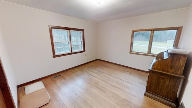 unfurnished room with a healthy amount of sunlight, light wood-type flooring, and crown molding