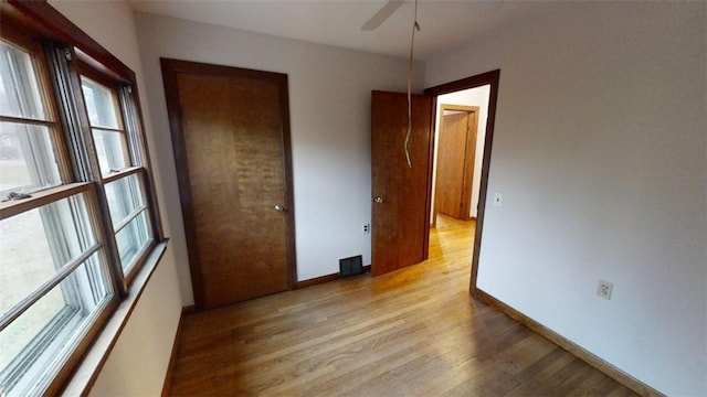 unfurnished bedroom with ceiling fan, light wood-type flooring, and a closet