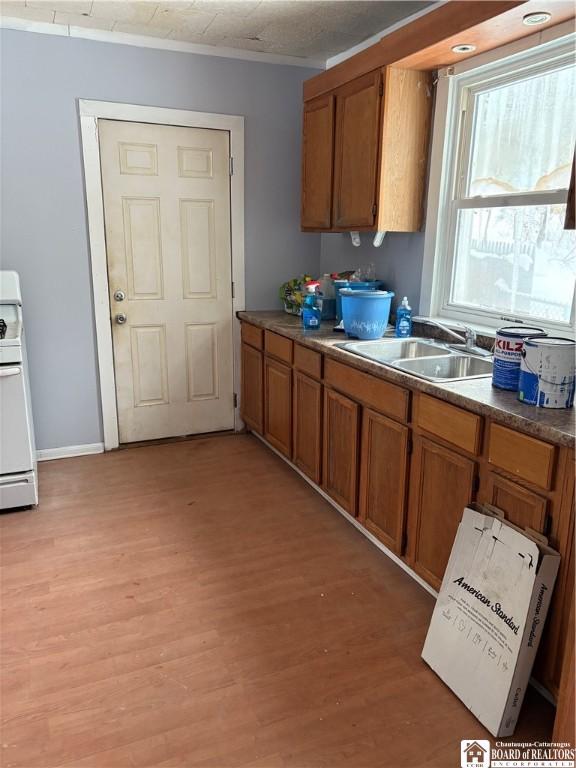 kitchen featuring white range with electric cooktop, crown molding, sink, and light hardwood / wood-style flooring