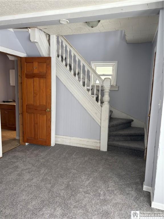 staircase featuring wood walls, carpet floors, and lofted ceiling