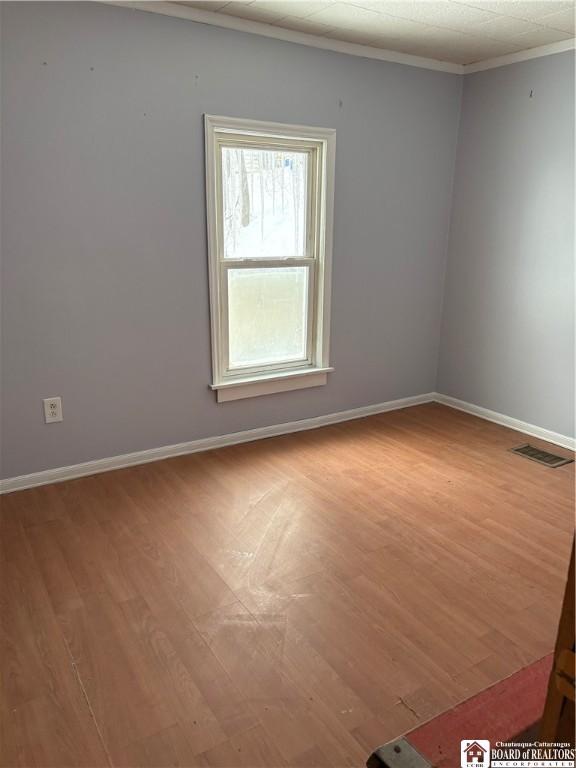 empty room with crown molding and light hardwood / wood-style flooring