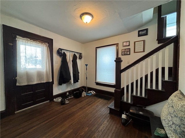 foyer with dark hardwood / wood-style flooring, lofted ceiling, and a wealth of natural light