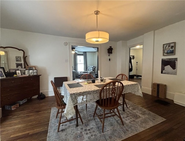 dining space with ceiling fan and dark wood-type flooring