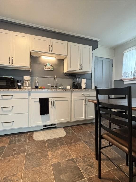 kitchen with white cabinets, ornamental molding, and sink